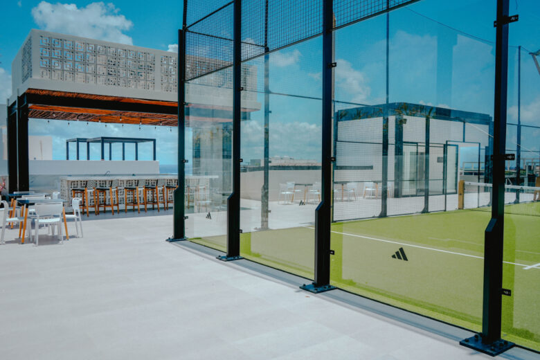 Rooftop con cancha de pádel y área social con bar y mobiliario moderno, dentro de un desarrollo residencial de lujo con departamentos en venta en Playa del Carmen, diseñado para ofrecer exclusividad, confort y vistas inigualables al Caribe.